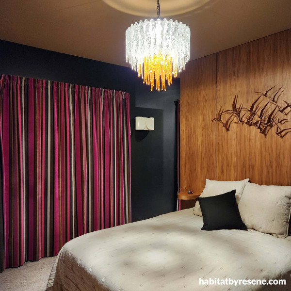 The walls in the main bedroom are in the dark, moody shade of Resene Nero, with a custom Resene gold for a touch of luxury. The ply feature wall is finished in Resene Aquaclear satin.  